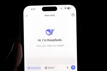 Смартфон в руке с запущенным интерфейсом чат-бота DeepSeek в темноте