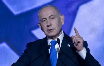 Israeli Prime Minister Benjamin Netanyahu delivering a speech in front of a blue screen