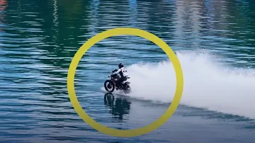 Мотоциклист на модифицированном мотоцикле MX450 едет по водной глади реки, оставляя пенный след