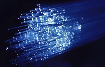 A bundle of glowing blue optical fibers demonstrating high-speed petabit-per-second data transmission technologies