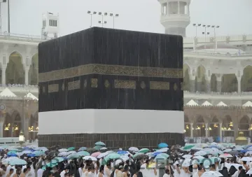 Die Kaaba in Mekka bei strömendem Regen mit einer Menschenmenge von Pilgern unter Regenschirmen