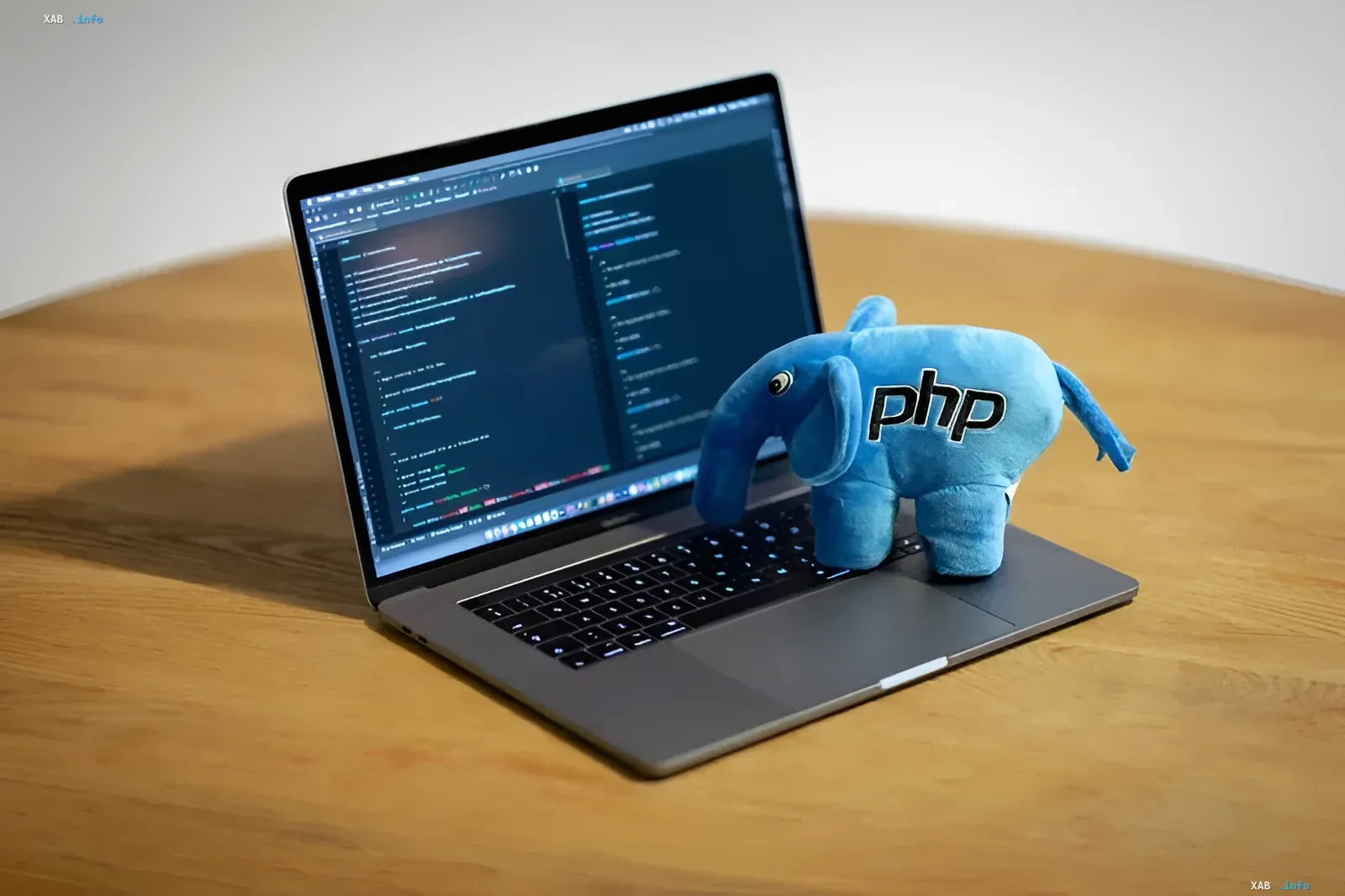 Ноутбук с открытым исходным кодом и синяя плюшевая игрушка слона PHP на клавиатуре