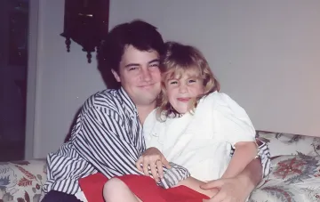 Matthew Perry hugging a young girl in a striped shirt on a sofa