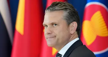 US-Verteidigungsminister Pete Hegseth vor dem Hintergrund von Flaggen bei einem Treffen