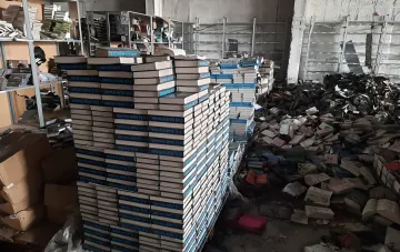 Zerstörtes Lager mit Bücherstapeln und Haufen von Druckerzeugnissen nach Beschuss