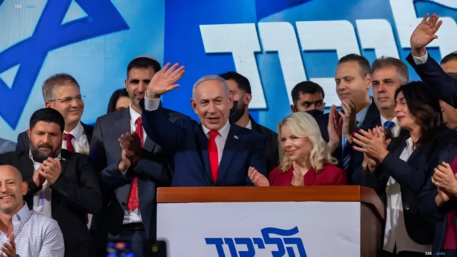 Benjamin Netanyahu waves to supporters from a podium surrounded by party members during Israeli elections