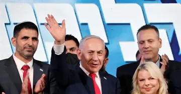 Der israelische Premierminister Benjamin Netanyahu winkt mit erhobener Hand im Kreis von Parteifolgen während der Wahlen