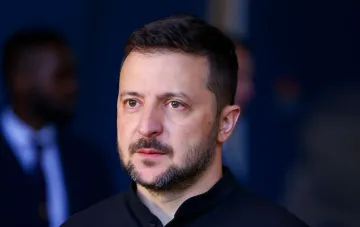 Президент Украины Владимир Зеленский выступает на международном мероприятии в черной футболке.