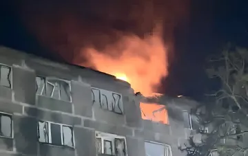 Горящий верхний этаж жилого здания ночью после попадания дрона в Днепре