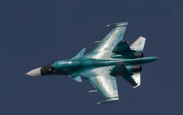 Российский истребитель-бомбардировщик Су-34 в полете на фоне ярко-синего неба