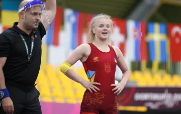 Украинская борчиха в красном трико стоит на ковре во время чемпионата мира в Астане