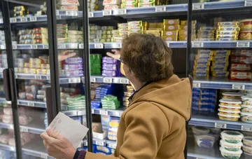 Женщина выбирает молочные продукты в холодильнике супермаркета в Киеве