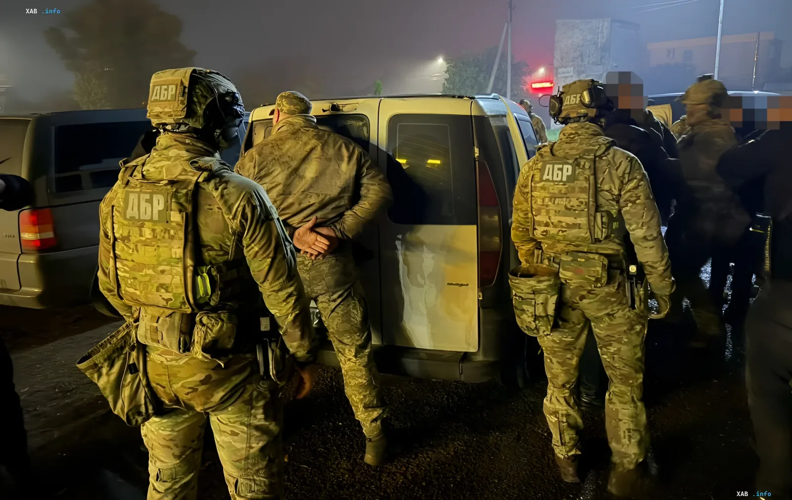 Militärpersonal in Camouflage-Uniformen mit DBR-Kennzeichnungen führt nachts eine Spezialeinsatzoperation zur Festnahme einer Person an einem weißen Kleinbus durch