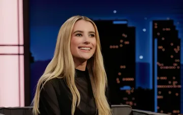 Emma Roberts lächelt in einem schwarzen Abend-Outfit während einer TV-Show-Aufzeichnung