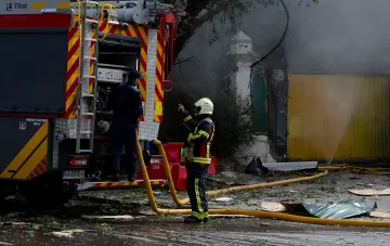 Feuerwehrauto und Einsatzkräfte bei den Löscharbeiten nach dem nächtlichen Angriff auf ein Unternehmen in Krementschuk
