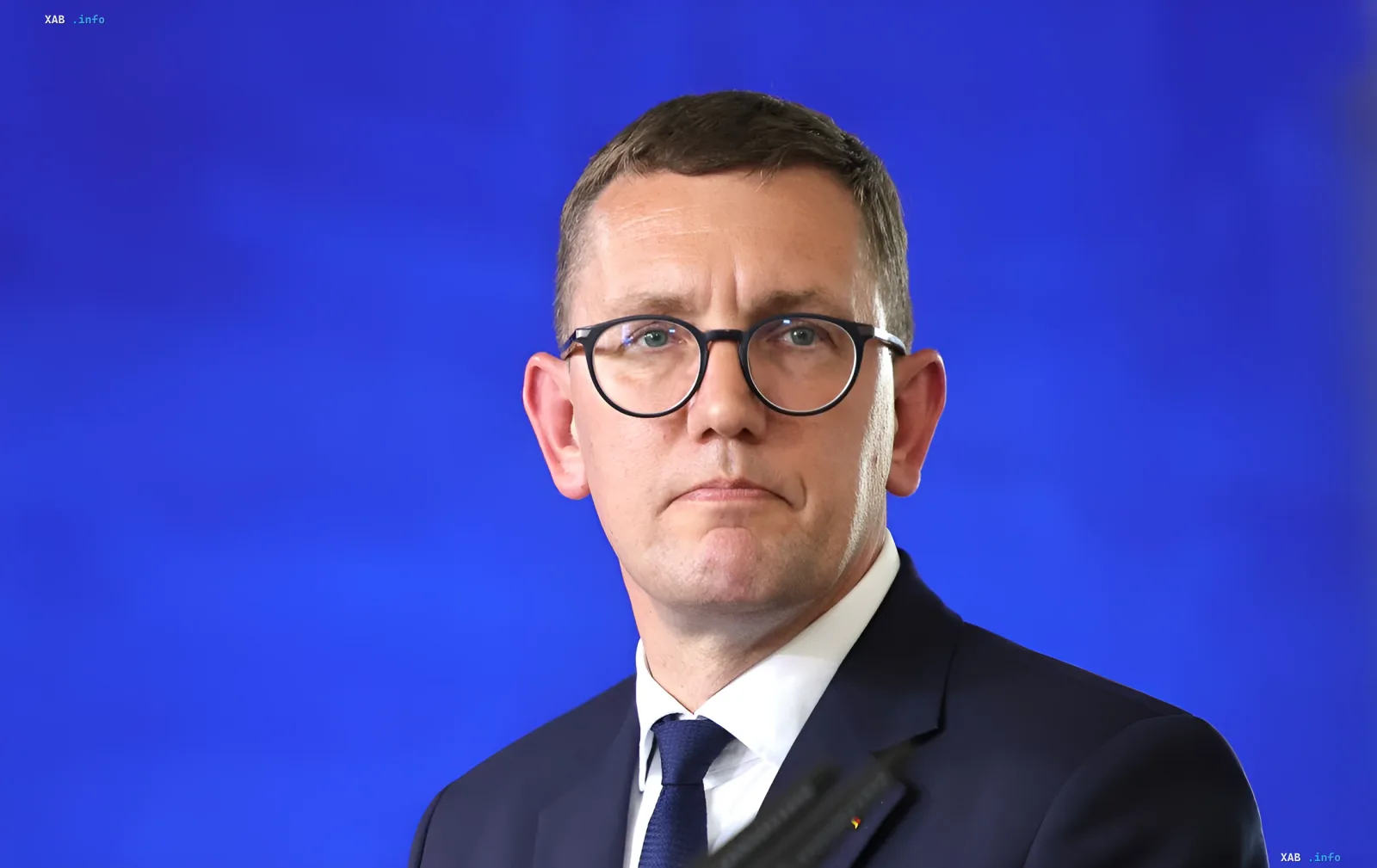 Премьер-министр Эстонии Кристен Михал в костюме и очках на синем фоне