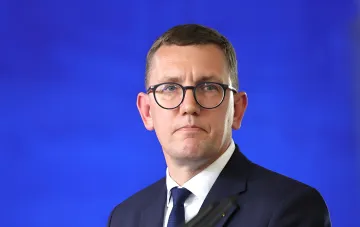 Премьер-министр Эстонии Кристен Михал в костюме и очках на синем фоне