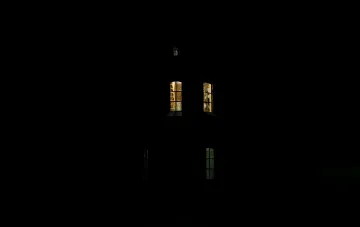 Темна будівля вежі з кількома світлими вікнами посеред нічного блекауту