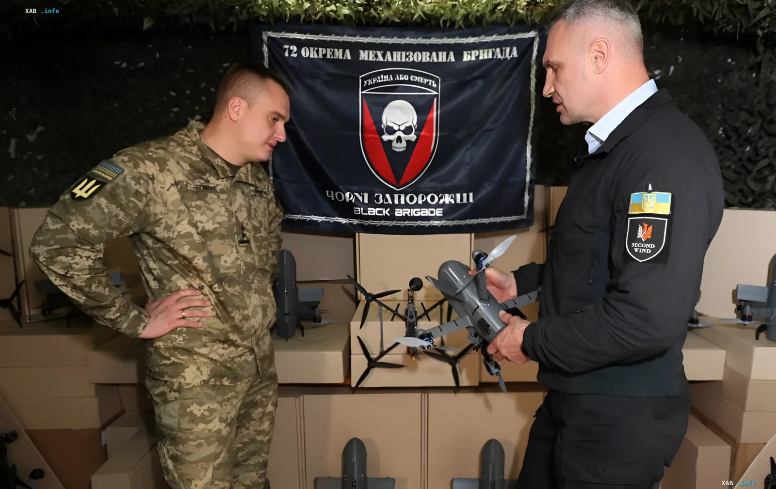 Виталий Кличко осматривает новую партию дронов вместе с бойцом ВСУ на фоне флага 72-й бригады
