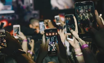 A crowd of people at a concert holding up smartphones to record video in the dark