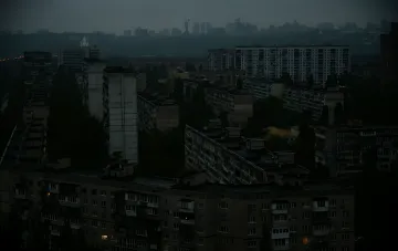 Panoramic view of a Kyiv residential district at dusk with apartment windows plunged into darkness due to power outages