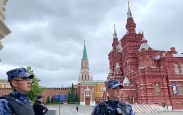 Armed officers in uniform stand against the background of a historic building and Kremlin tower in Moscow