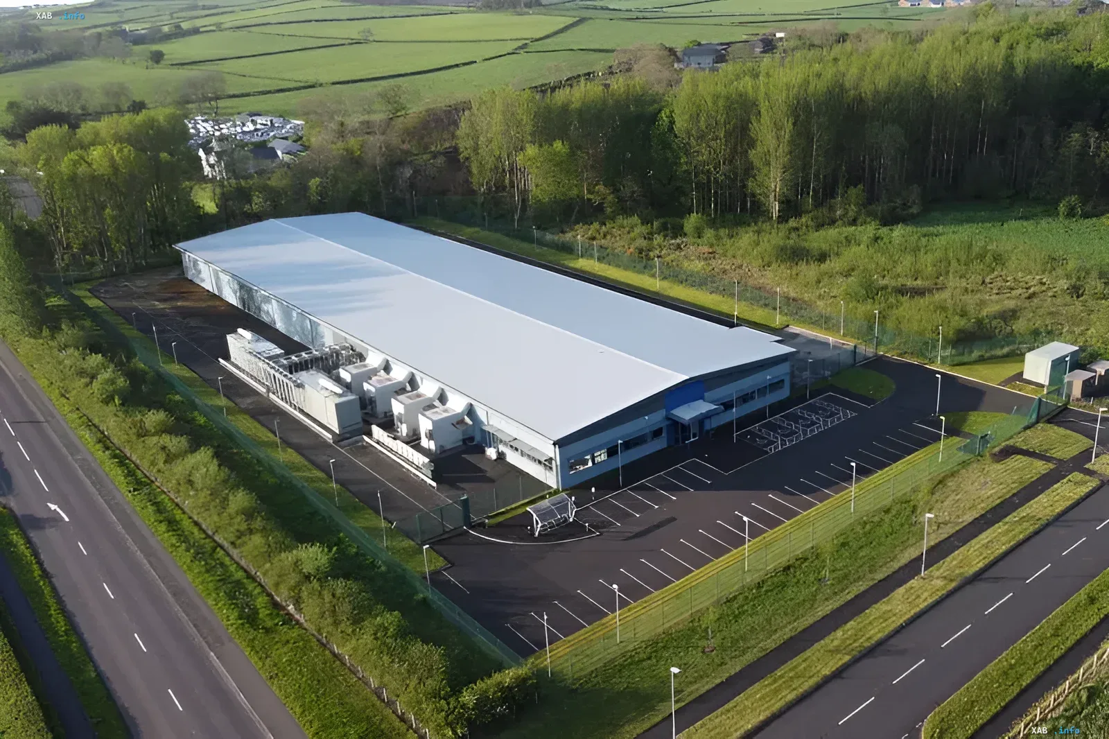 Aerial view of a large data center with cooling fans and surrounding green area