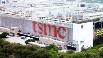 Aerial view of a large modern TSMC semiconductor manufacturing plant with a large red logo