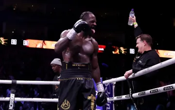 Deontay Wilder celebrating a victory inside the boxing ring with raised arms